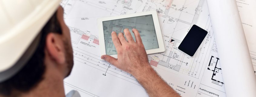 Planung und Entwicklung im Bauwesen - Architekt mit Tablet und techn. Zeichnung am Arbeitsplatz